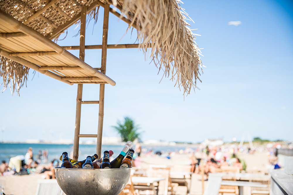 Öl i skål på kylning, i bakgrunden folk på sandstrand.
